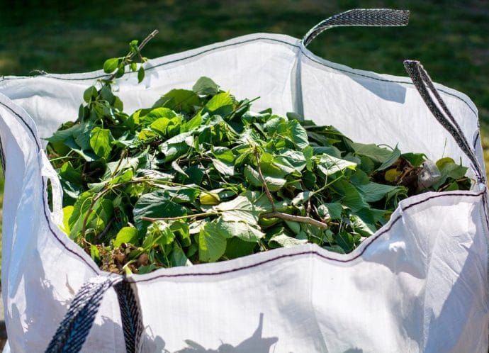 Large white rental bag with organic green garden waste. Large white rental bag with organic green garden waste.